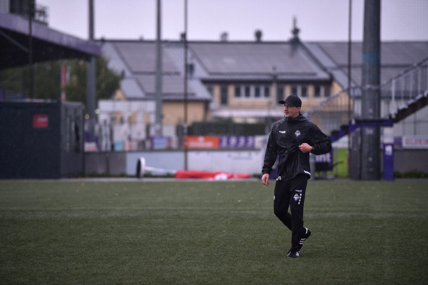 Predrag Bibu im Regen auf dem Kunstrasenplatz, im Hintergrund eine Tribüne
